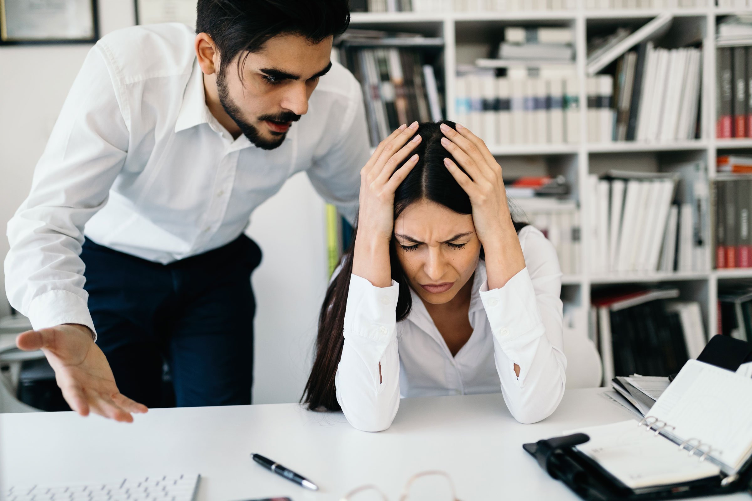A man reprimands a stressed woman at her desk. | Forensic Discovery