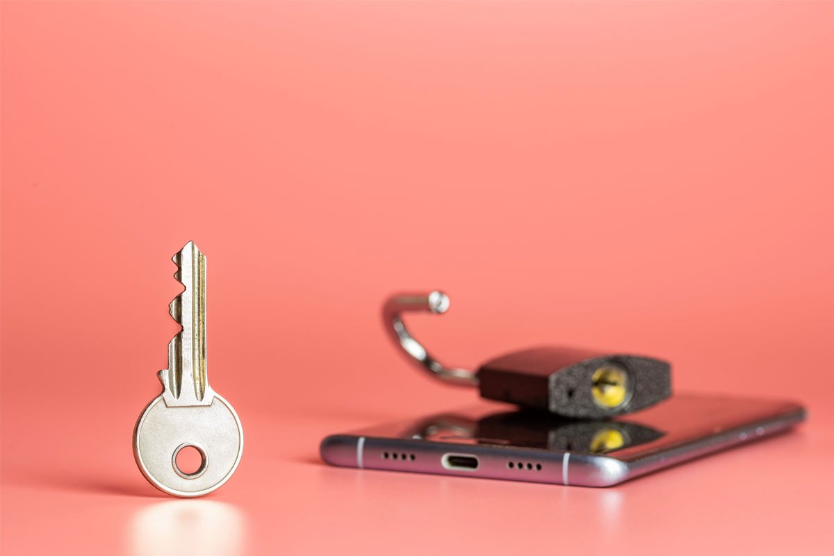 A key and an unlocked padlock resting on a smartphone against a pink background. | Forensic Discovery