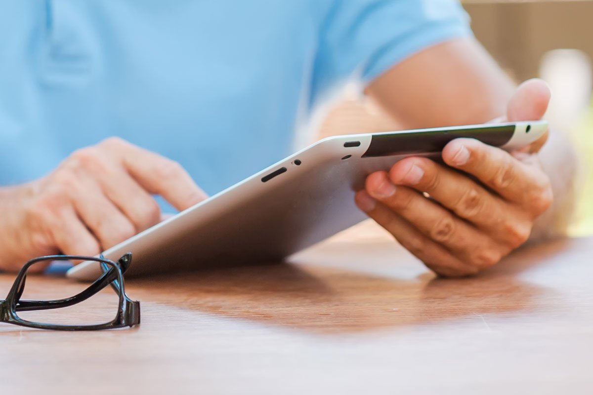 Person using a tablet with glasses nearby. | Forensic Discovery