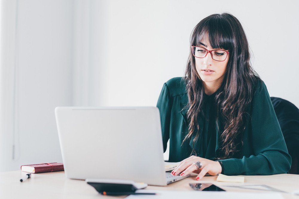 Woman with long brown hair wearing glasses works on a laptop. | Forensic Discovery